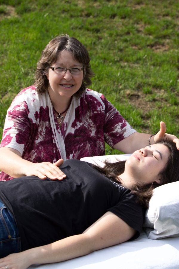 A woman is giving reiki to another person.