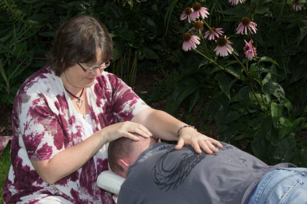 A woman is giving a man an acupuncture treatment.